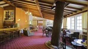 Un restaurante acogedor con vigas de madera, un tocón de árbol como centro de mesa y una alfombra roja con estampado.