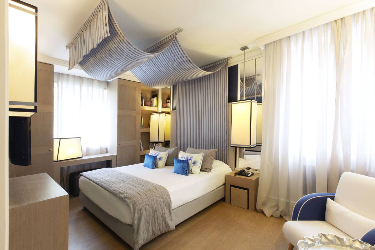 A modern hotel room with a large bed, bedside tables, a desk, and a chair.