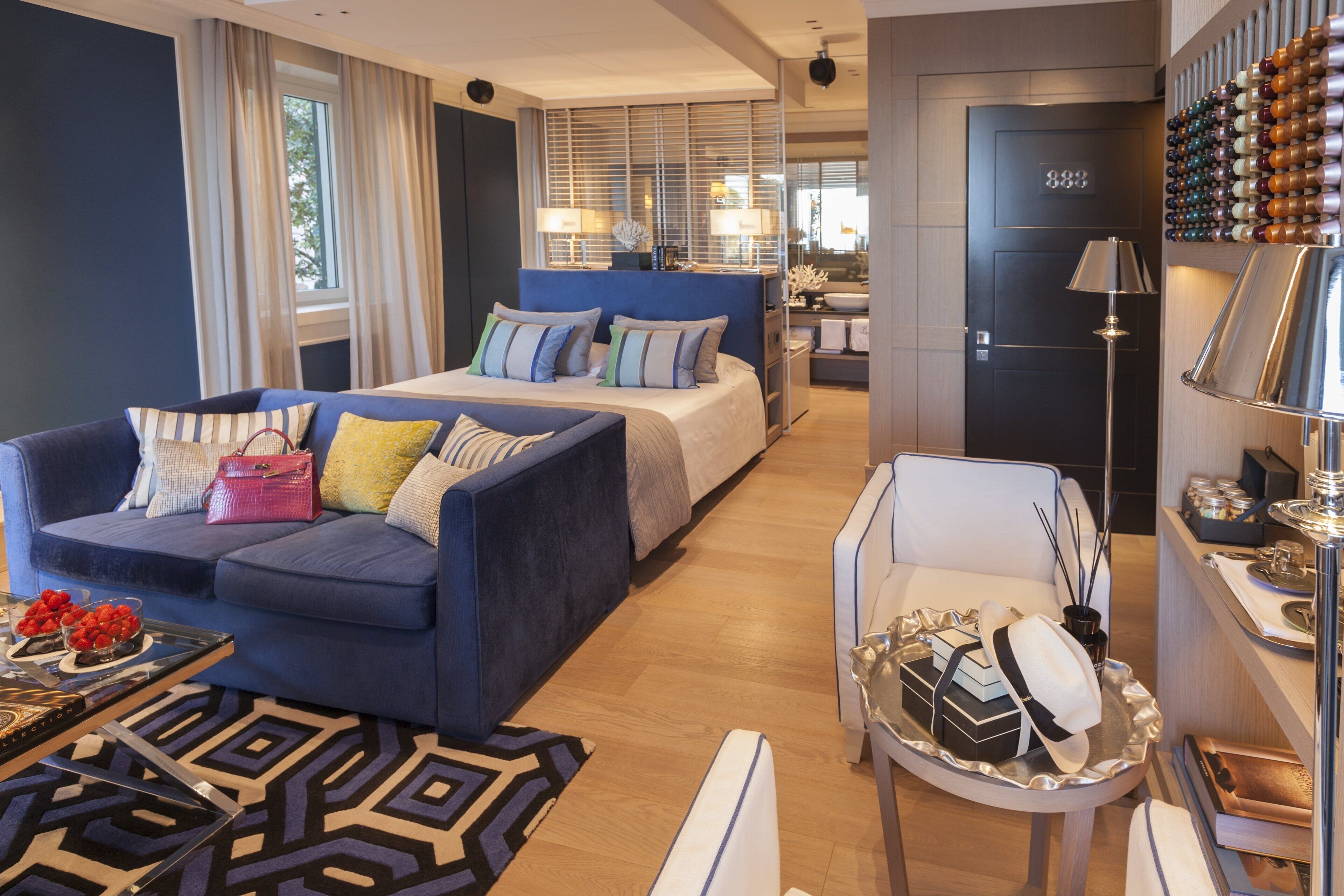 Ein modernes Hotelzimmer mit einem großen Bett, einer Couch, einem kleinen Tischchen mit Tablett und einem Sessel.