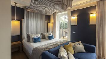 Ein modernes Schlafzimmer mit einem großen Bett, einem blauen Sofa und Blick ins Freie.