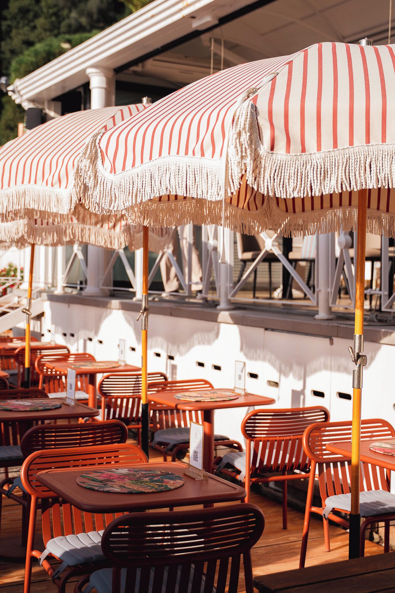 Outdoor seating with striped umbrellas and wooden tables.