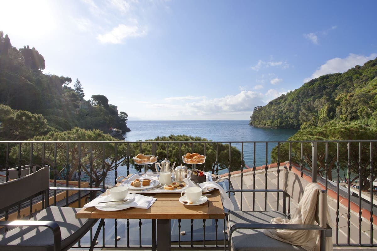 A table set for breakfast with a scenic view of the sea and hills.