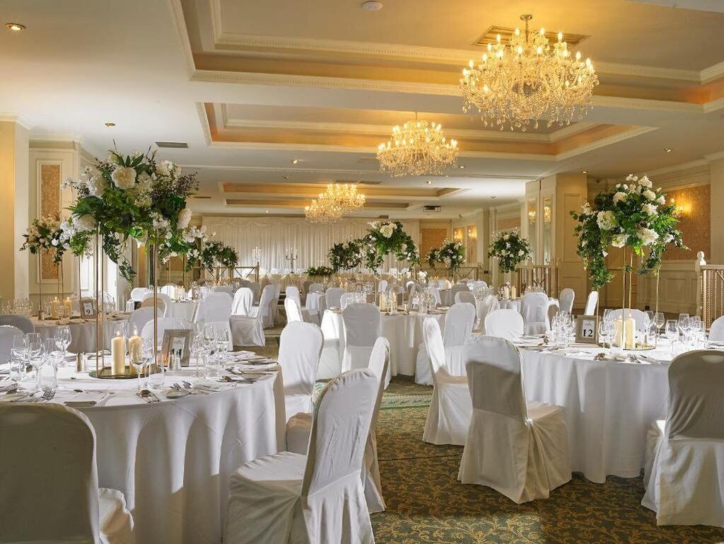 A banquet hall with round tables, white tablecloths, and floral centerpieces.
