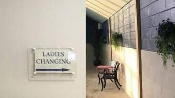 Un pasillo con un cartel que indica 'Ladies Changing' y otro cartel que dice 'Zona poco profunda 0,9m'.