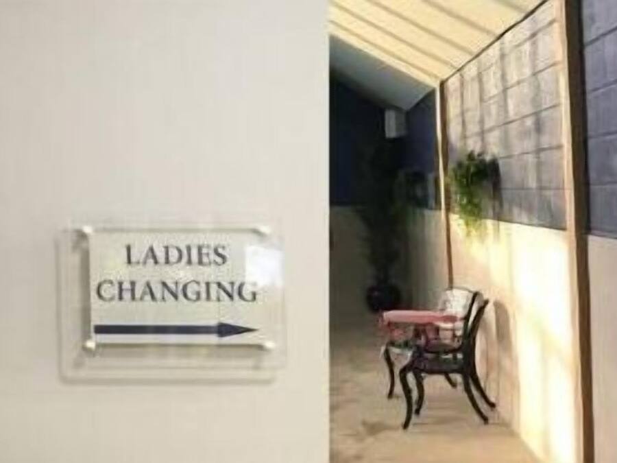 Un pasillo con un cartel que indica 'Ladies Changing' y otro cartel que dice 'Zona poco profunda 0,9m'.