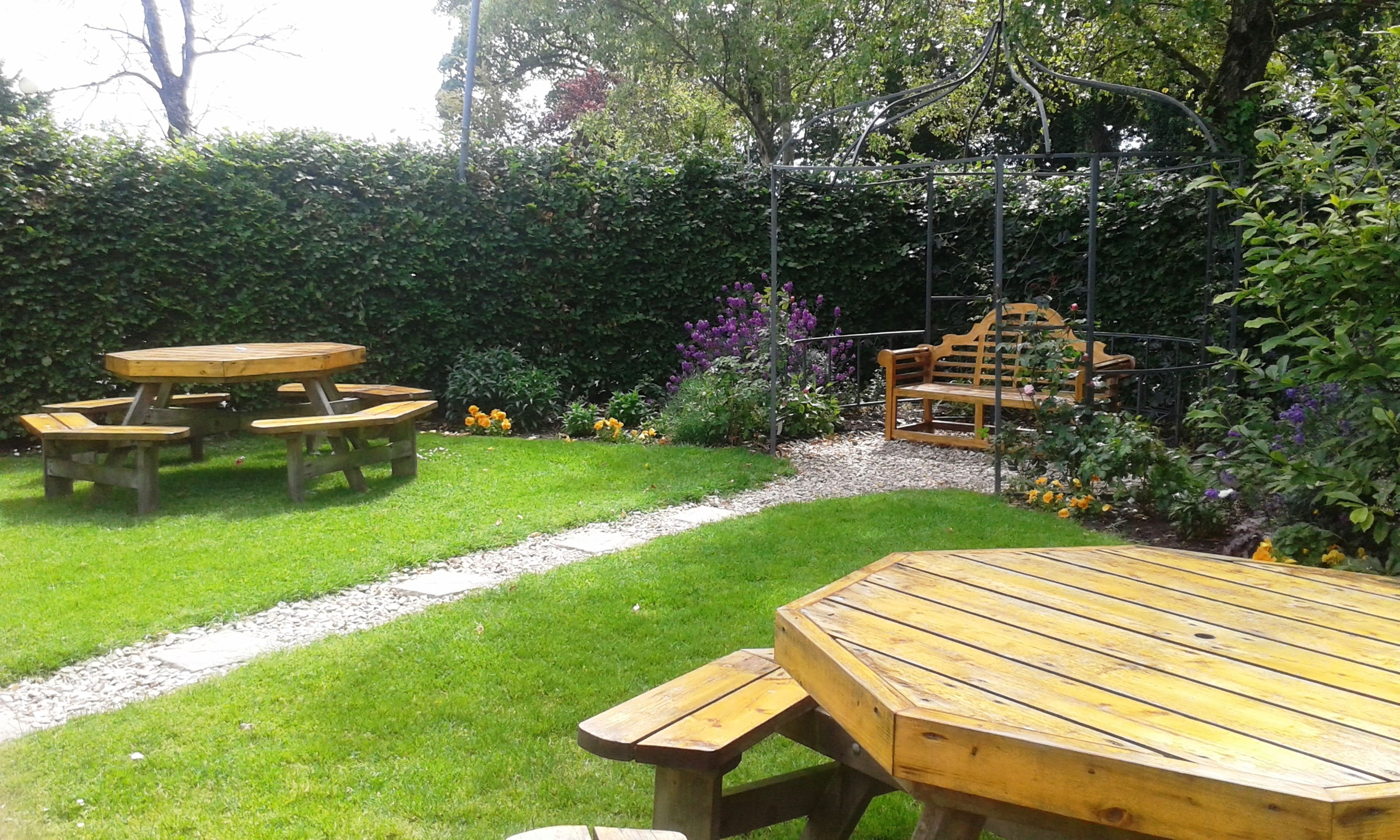 A garden with a picnic table and a bench.