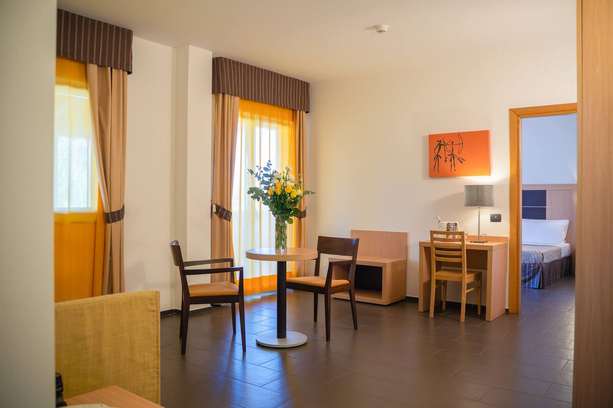 Habitación de hotel con comedor, cama, escritorio y silla.