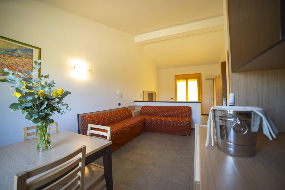 Un espacio habitable compacto con comedor, sofá y zona de cocina.