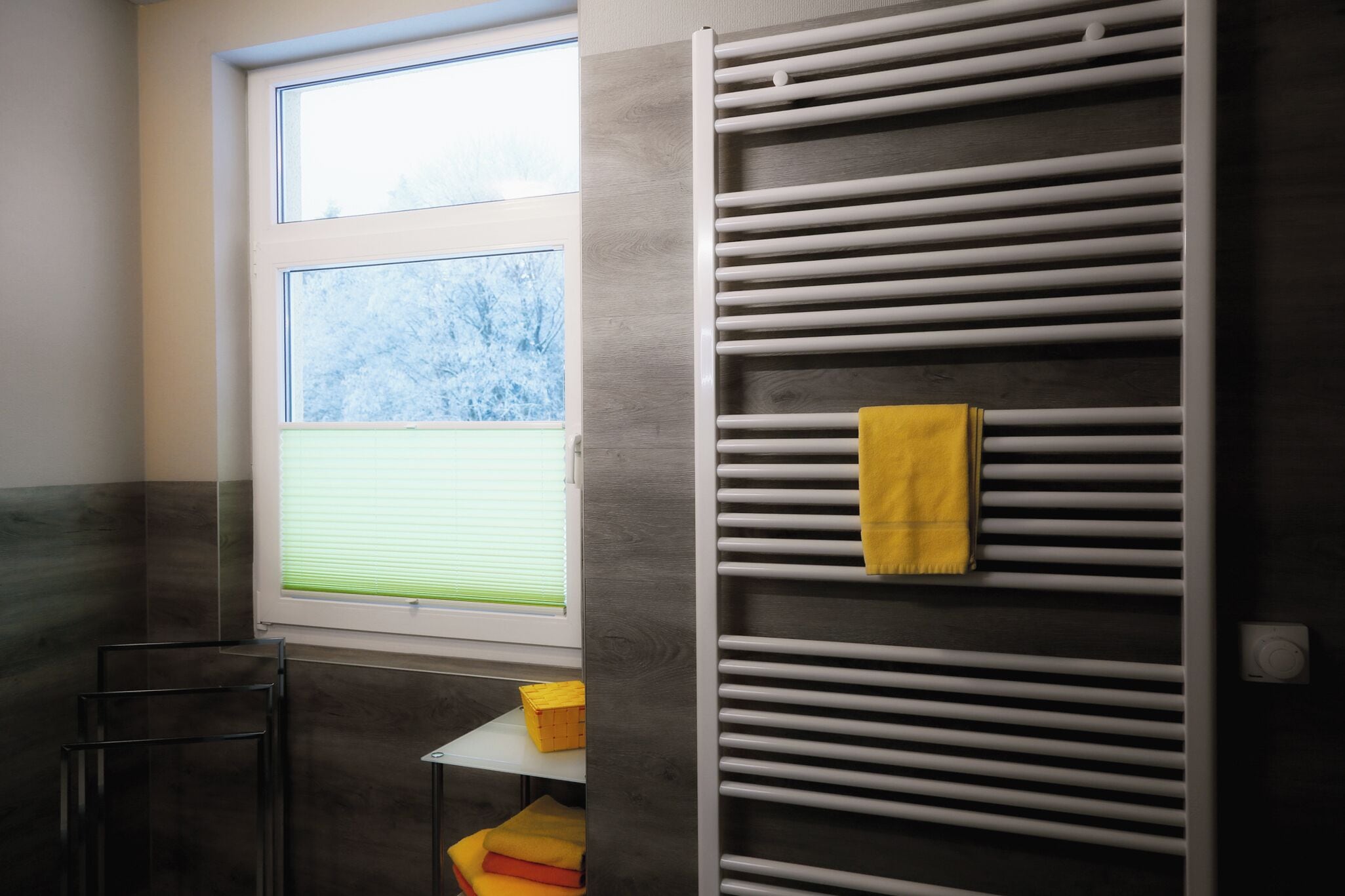 Ein Badezimmer mit Fenster, Handtuchhalter und Ablagefläche mit Handtüchern.