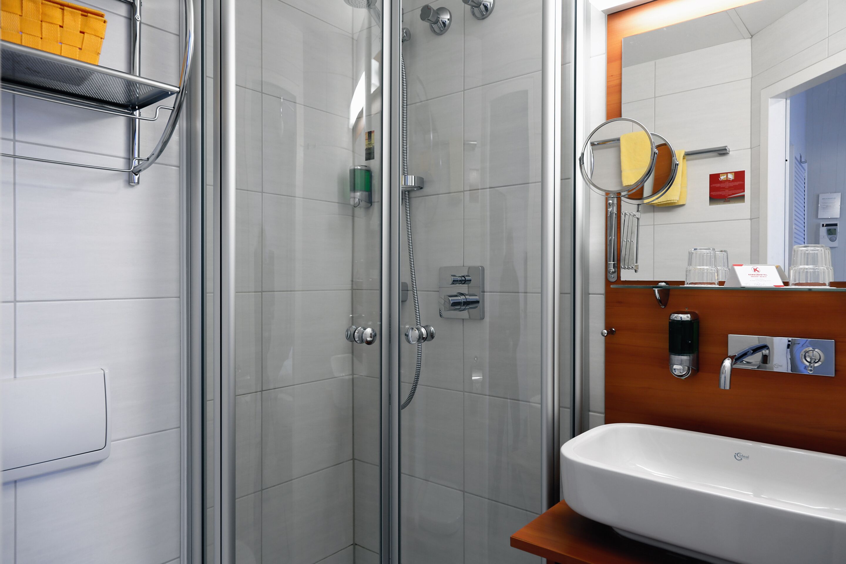 Een moderne badkamer met een douchecabine van glas, een wit wastafelmeubel en een houten opbergkast.