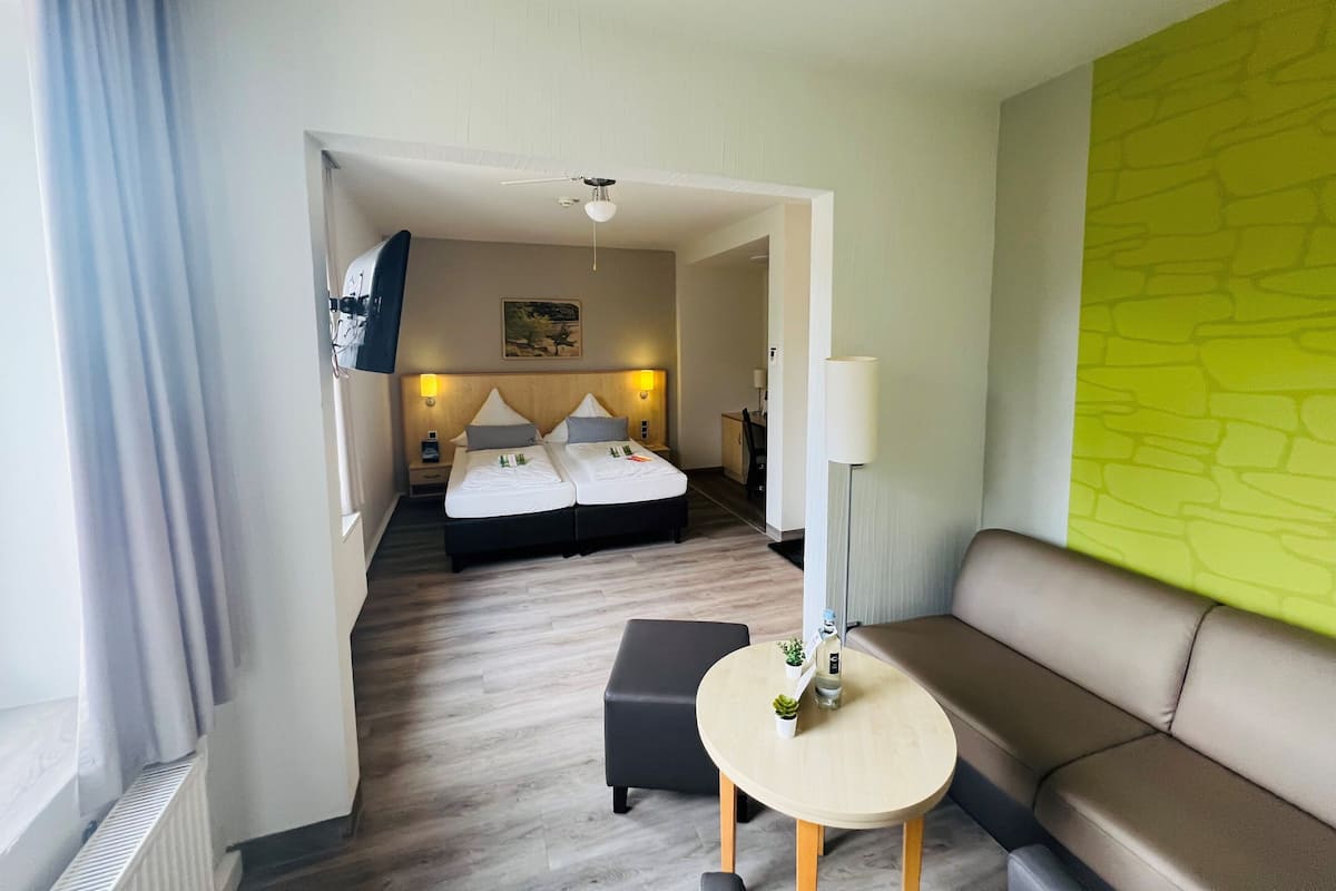 Une chambre d’hôtel avec un lit, un canapé, une petite table et une lampe.