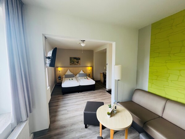 Una habitación de hotel con una cama, un sofá, una mesita y una lámpara.
