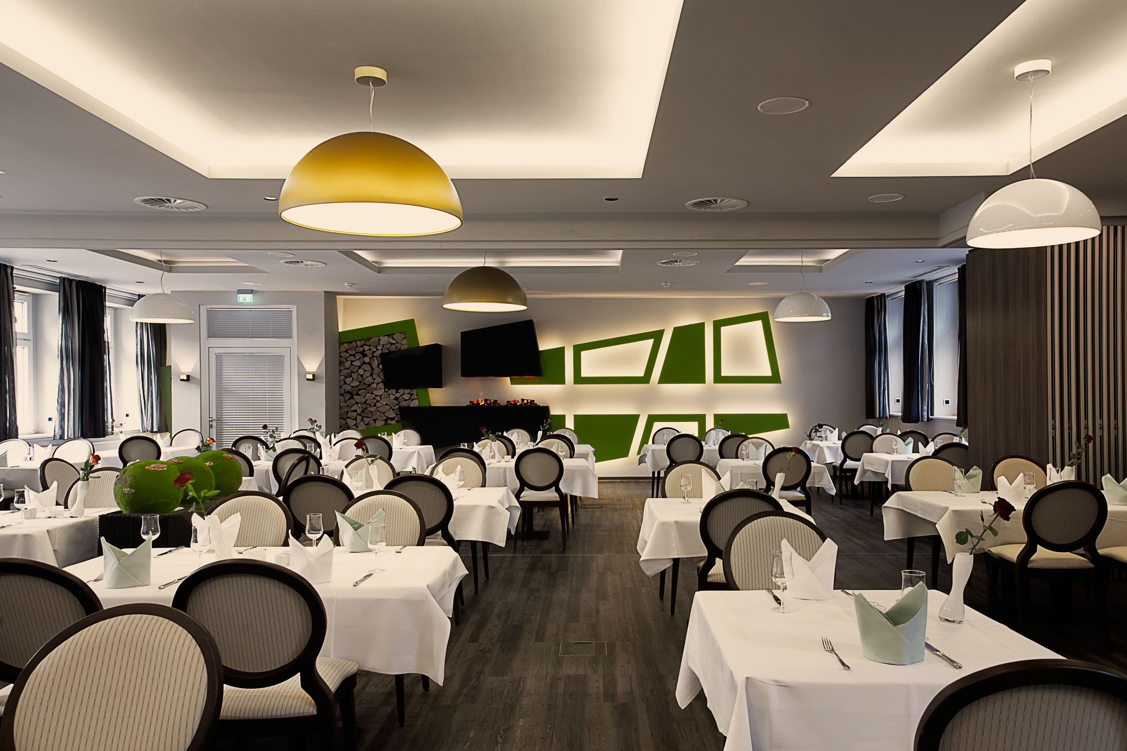 Un salón de conferencias con varias mesas y sillas, equipado con manteles blancos y copas.