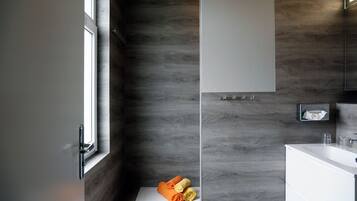 A modern bathroom with a large window, a white sink, and a wooden wall.