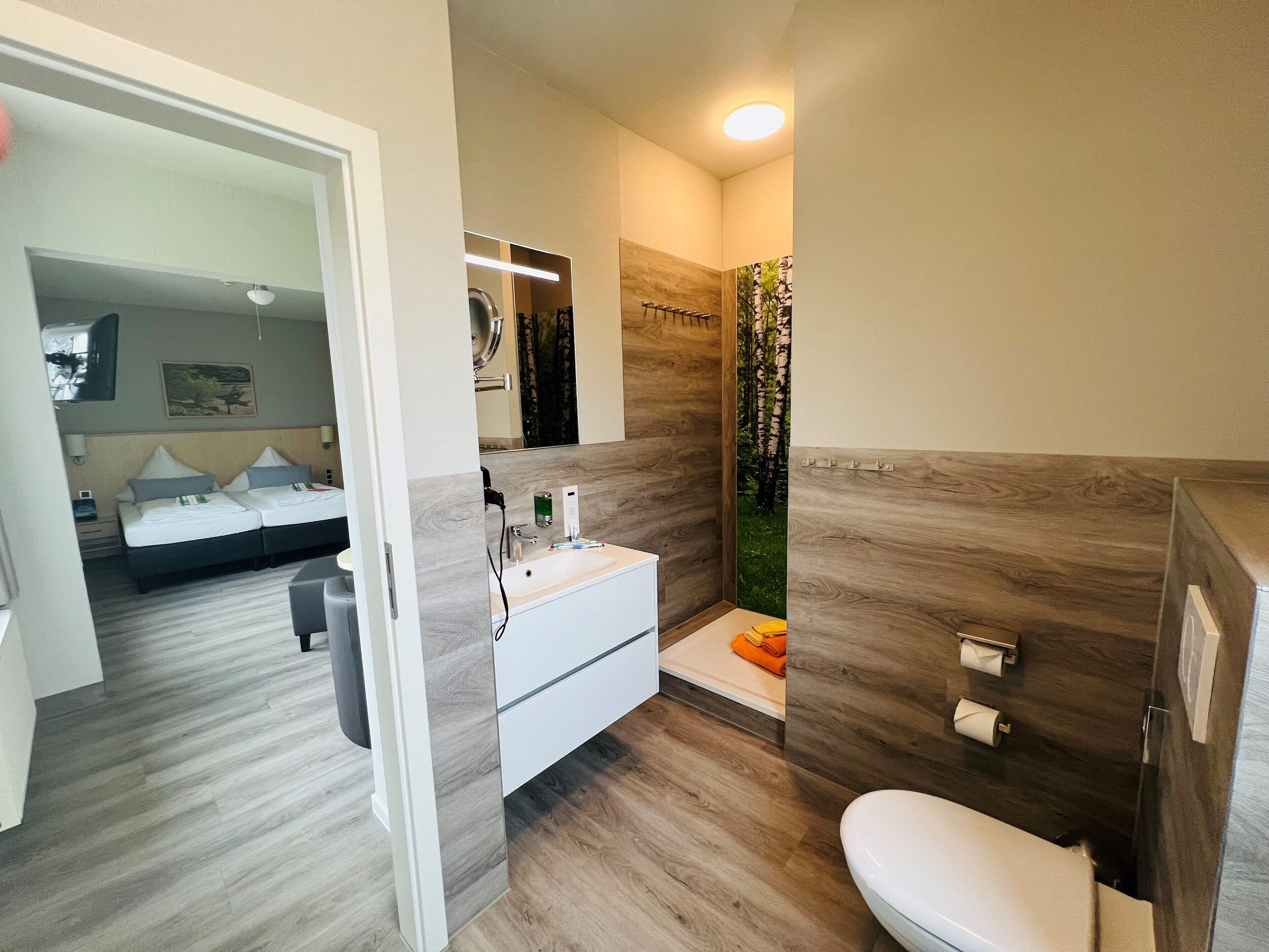 A modern bathroom with a shower, toilet, and sink.