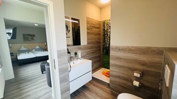 A modern bathroom with a shower, toilet, and sink.
