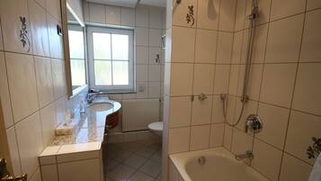 Un baño con bañera, lavabo, inodoro y ventana.