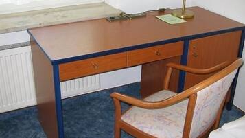 A wooden desk with a chair, a radiator, and a window.