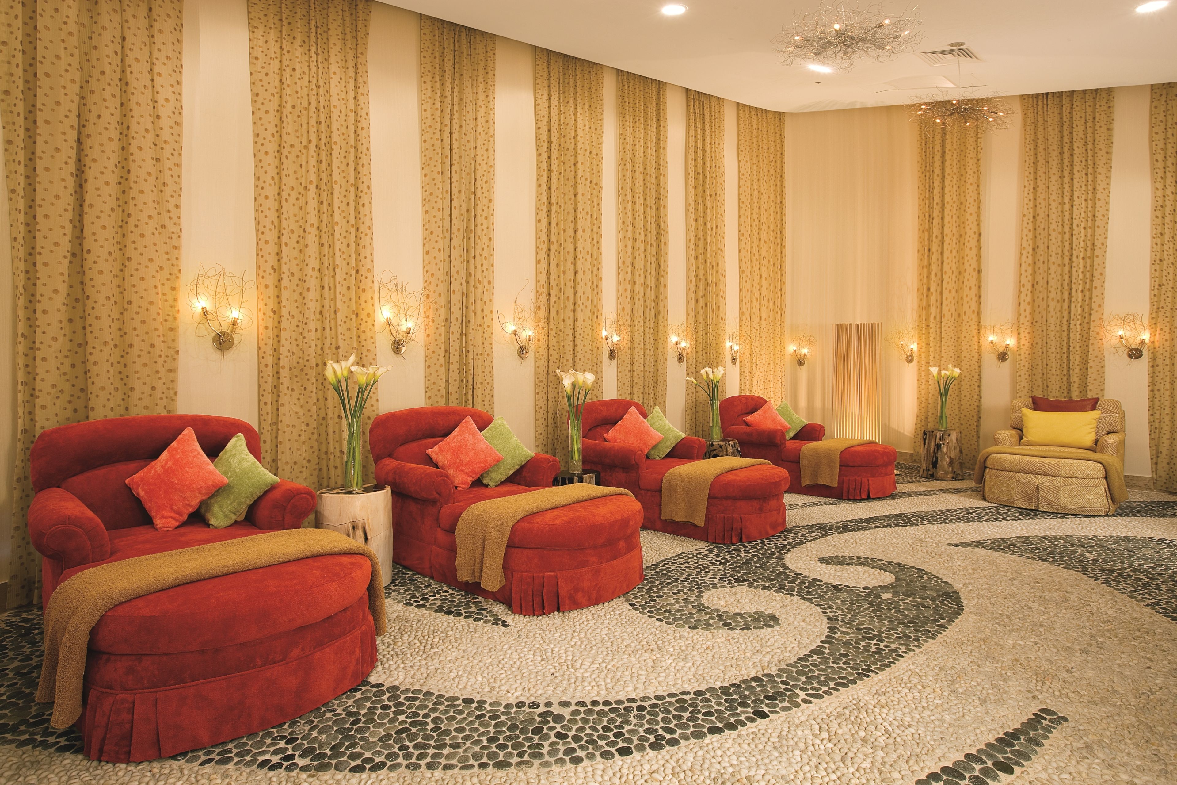 A room with multiple red sofas, a yellow armchair, and a patterned floor.