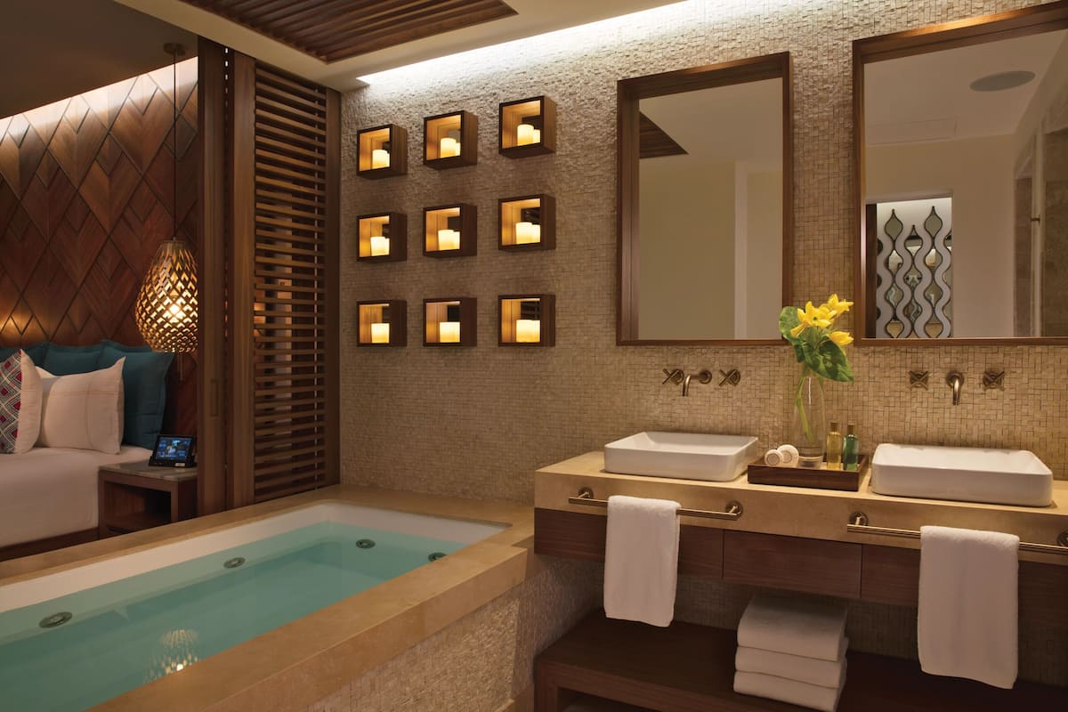 A modern bathroom with a bathtub, two sinks, and a large mirror.