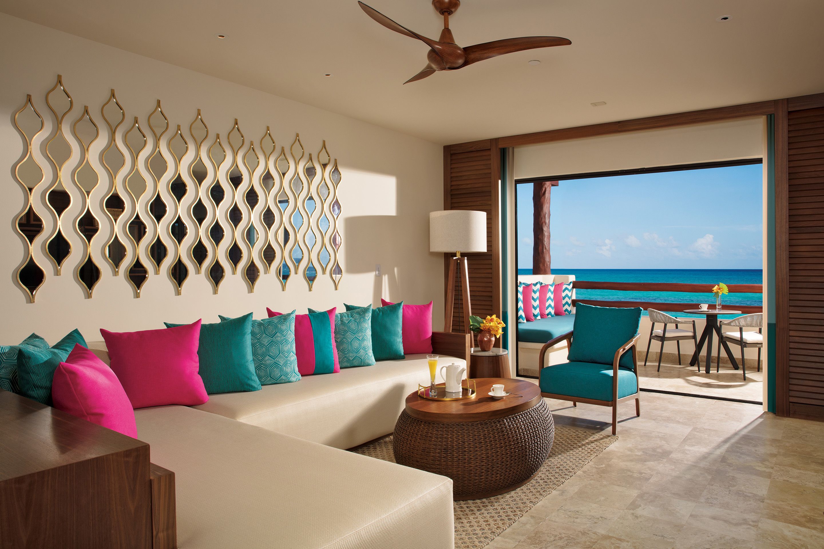 A modern hotel room with a large bed, a sofa, a coffee table, and a view of the ocean.