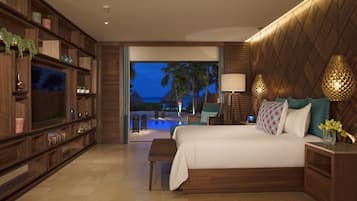 Habitación de hotel moderna con una cama grande, estanterías de madera, un televisor y vistas a una piscina y palmeras al anochecer.