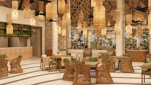 A spacious indoor area with wicker furniture, hanging wicker lamps, and a view of palm trees through a large window. - Secrets Maroma Beach Riviera Cancun - Adults Only - All inclusive (Playa del Carmen)