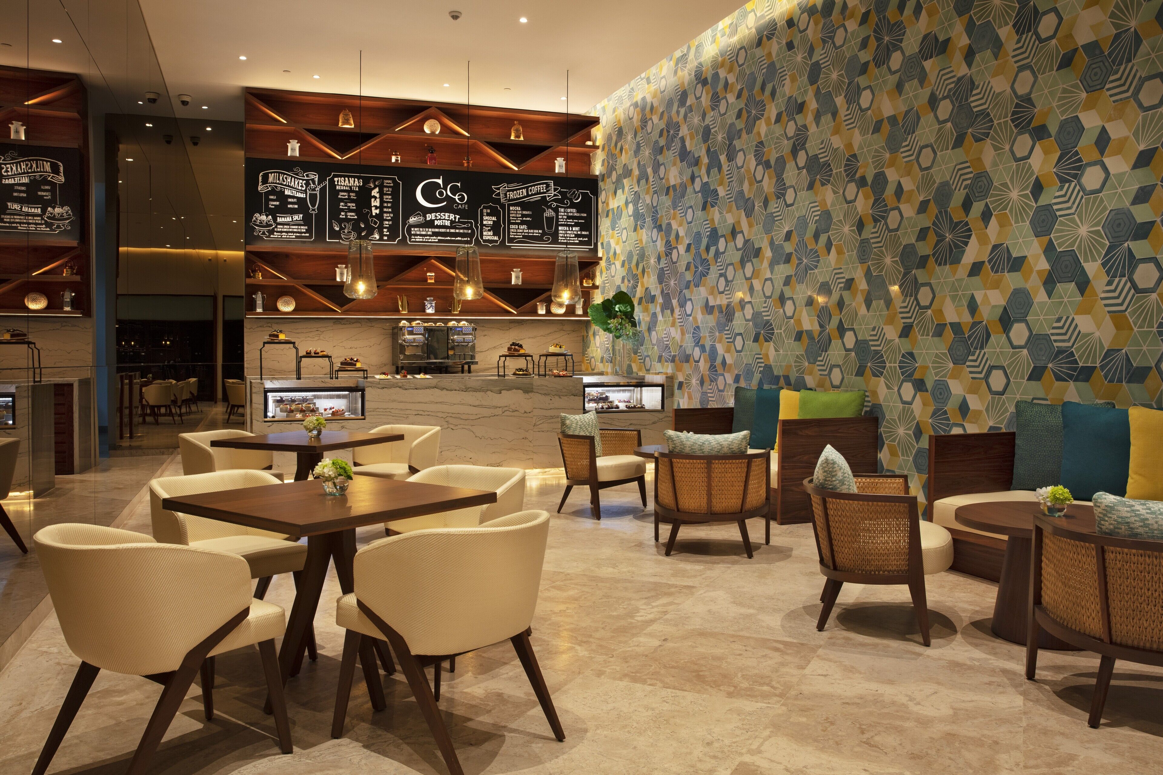 A modern lounge area with seating arrangements, a bar, and a patterned wall.