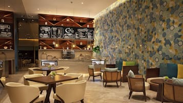 A modern lounge area with seating arrangements, a bar, and a patterned wall.
