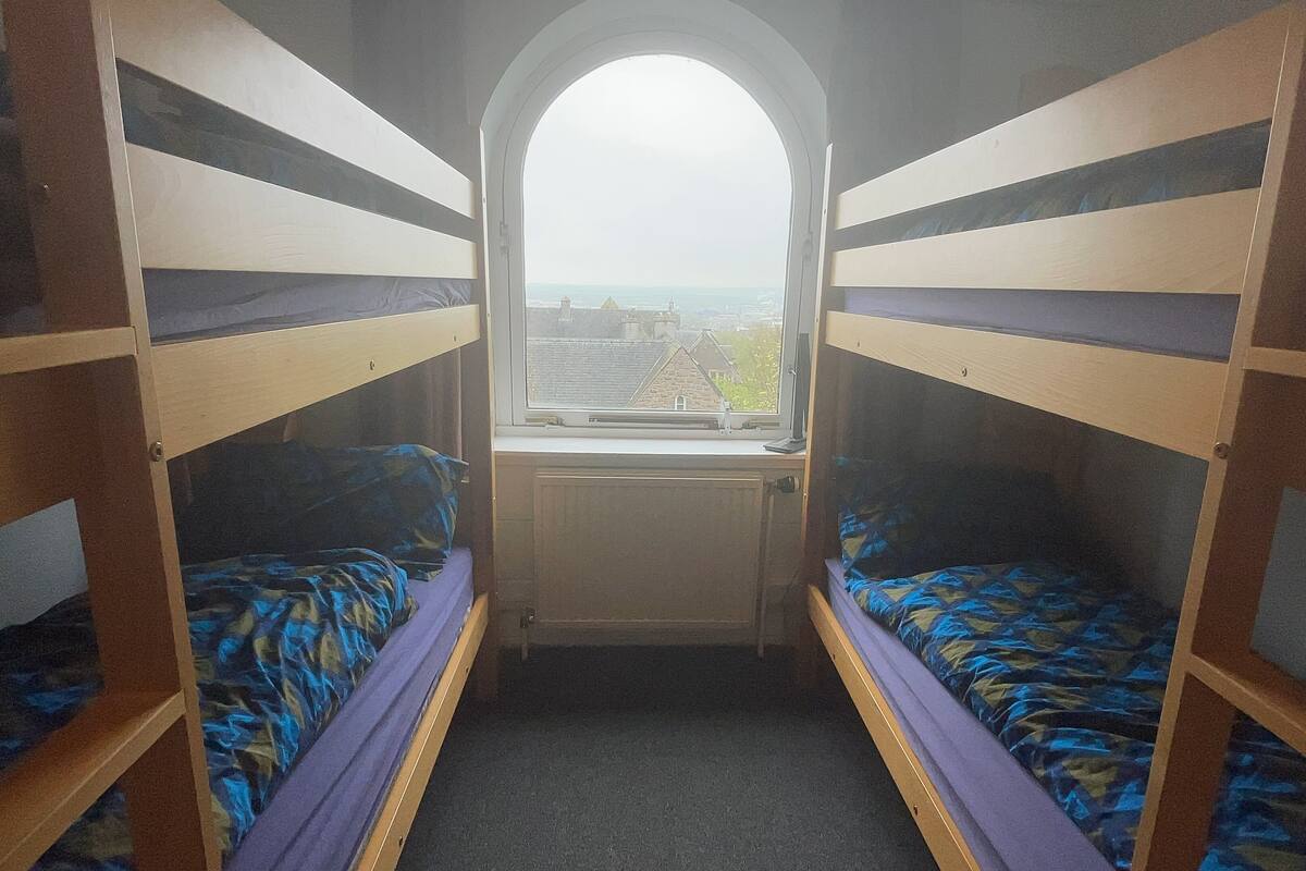 A narrow room with bunk beds and a window.