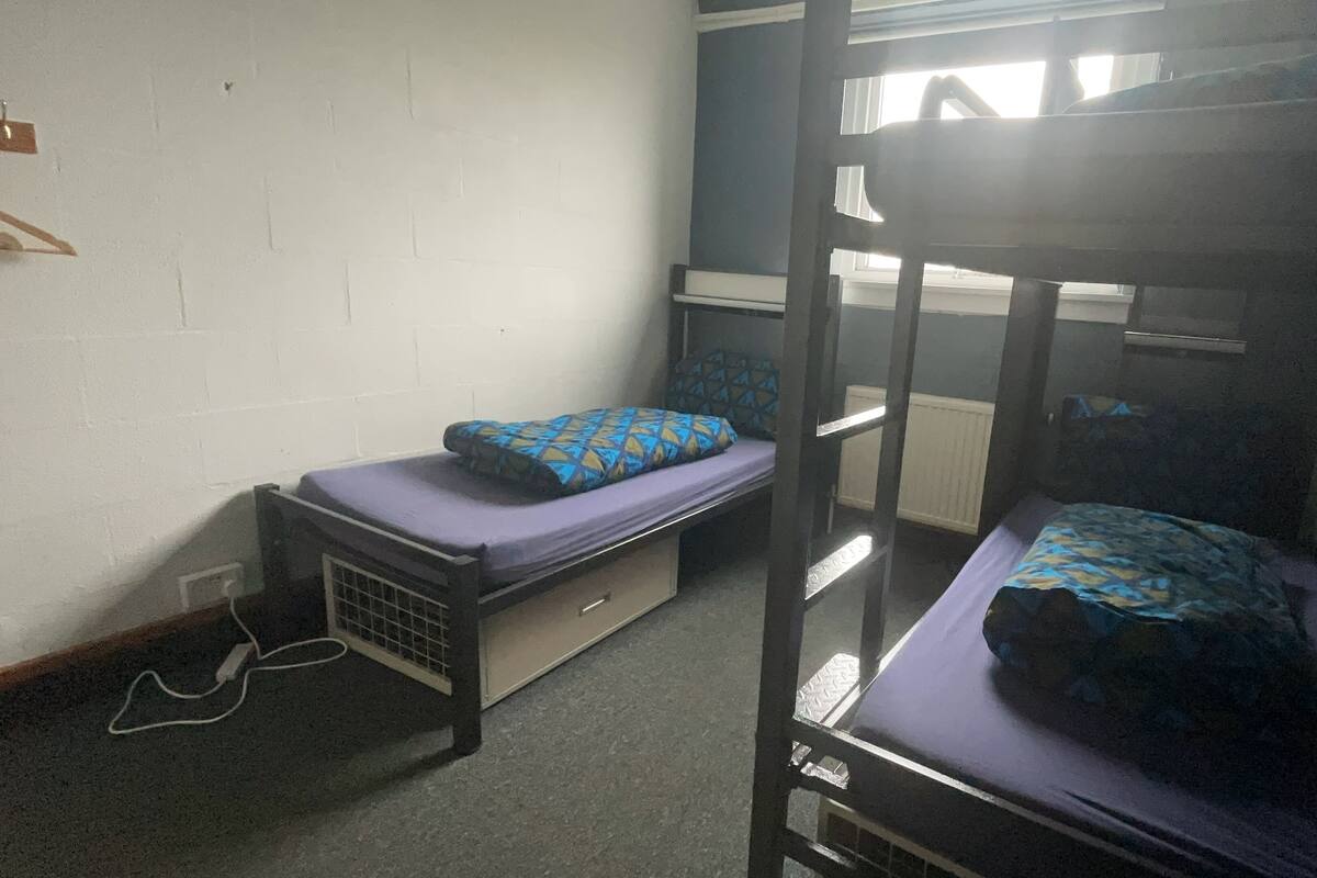 A bunk bed room with a window, a desk, and a chair.