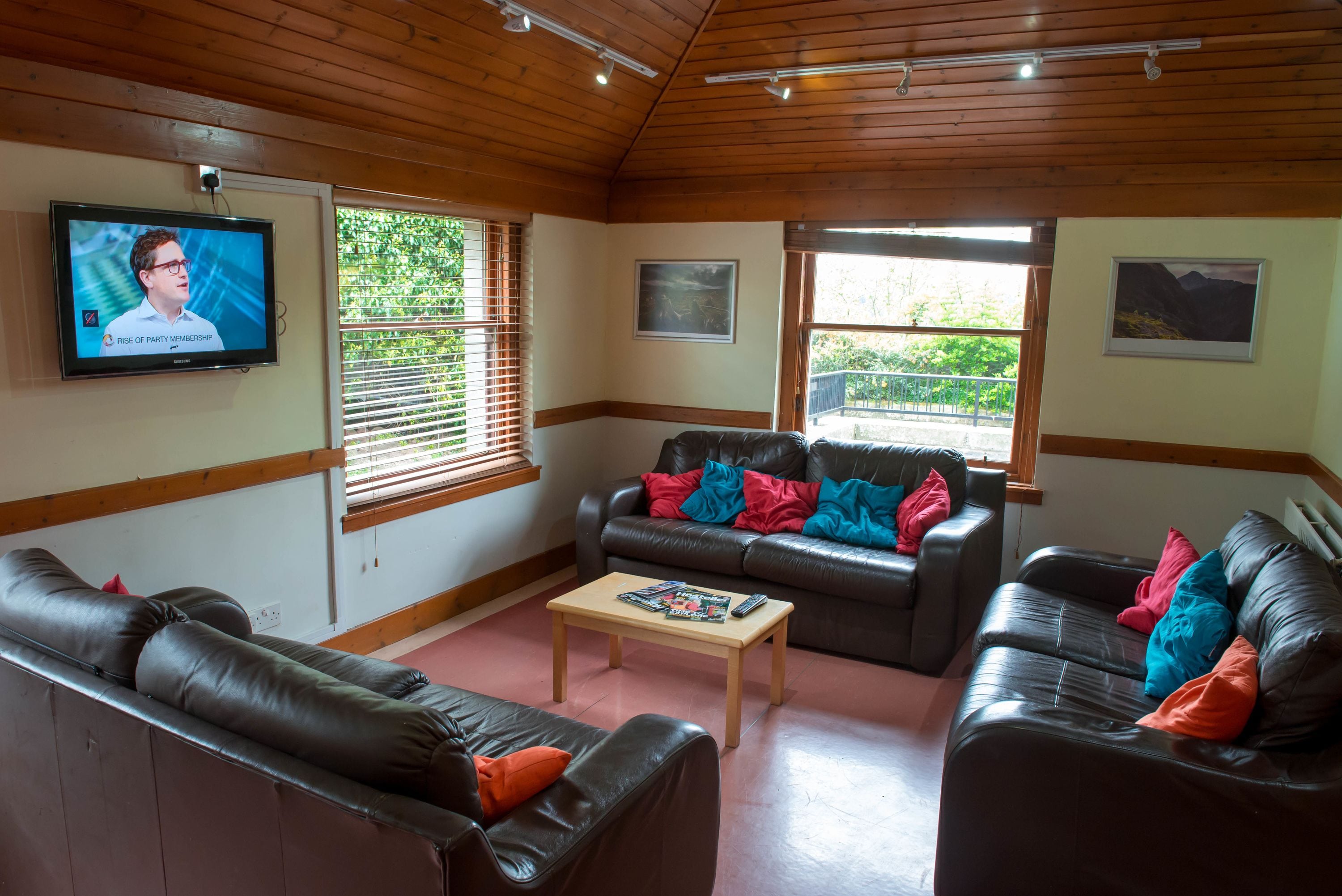 A living room with leather sofas, a coffee table, and a TV mounted on the wall.