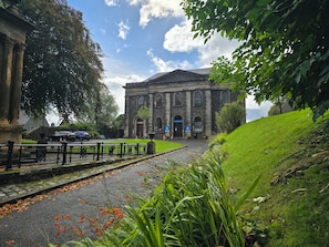 A building with classical architecture, a paved pathway, and a grassy area with plants. - Stirling Youth Hostel (Stirling)