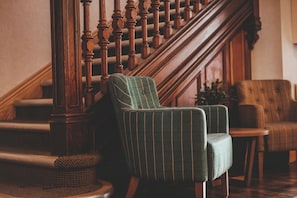 Een trap met houten spijbels, een met groen bekleden fauteuil en een houten bank.