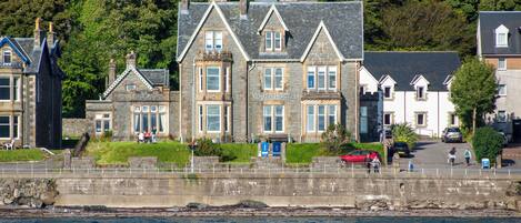 A coastal building with multiple windows and a stone facade, located near a body of water.