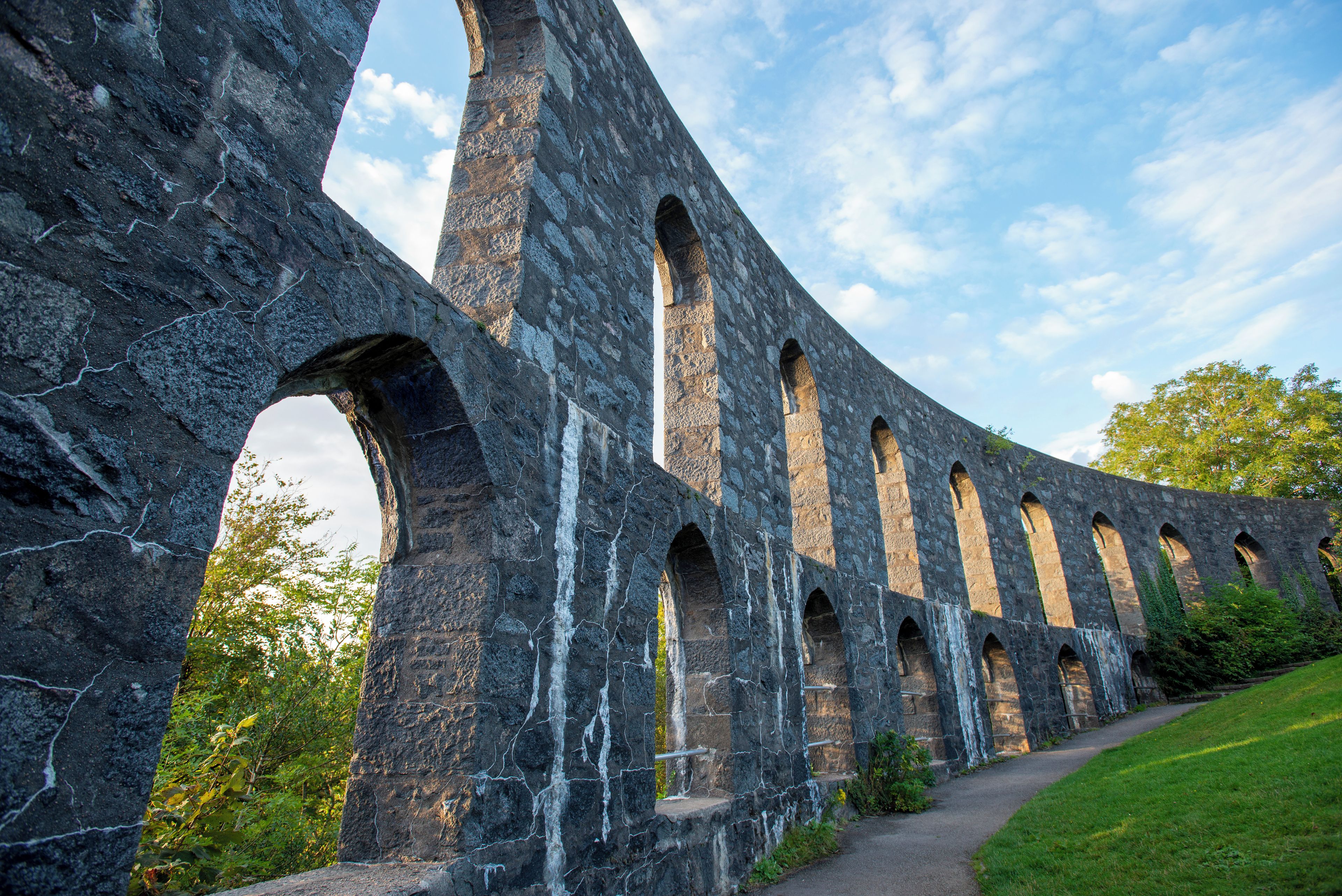 An ancient stone structure with multiple arched openings and a pathway leading to it.