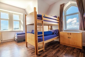Habitación con literas y vista al mar a través de un ventanal grande.