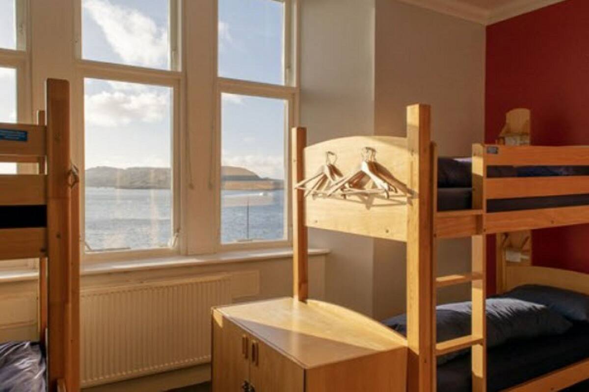 A bunk bed room with a view of a body of water through large windows.