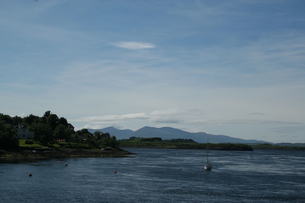A calm lake with a sailboat, a house on the shore, and mountains in the background. - Oban Youth Hostel (Oban)