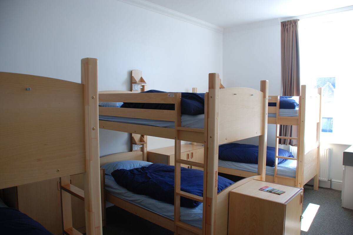 A bunk bed room with a desk and a window.