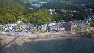 An aerial view of a coastal town with a mix of residential and commercial buildings, a prominent church, and a clear view of the coastline.