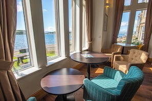 A room with a view of a body of water, a round table, and two chairs. - Oban Youth Hostel (Oban)