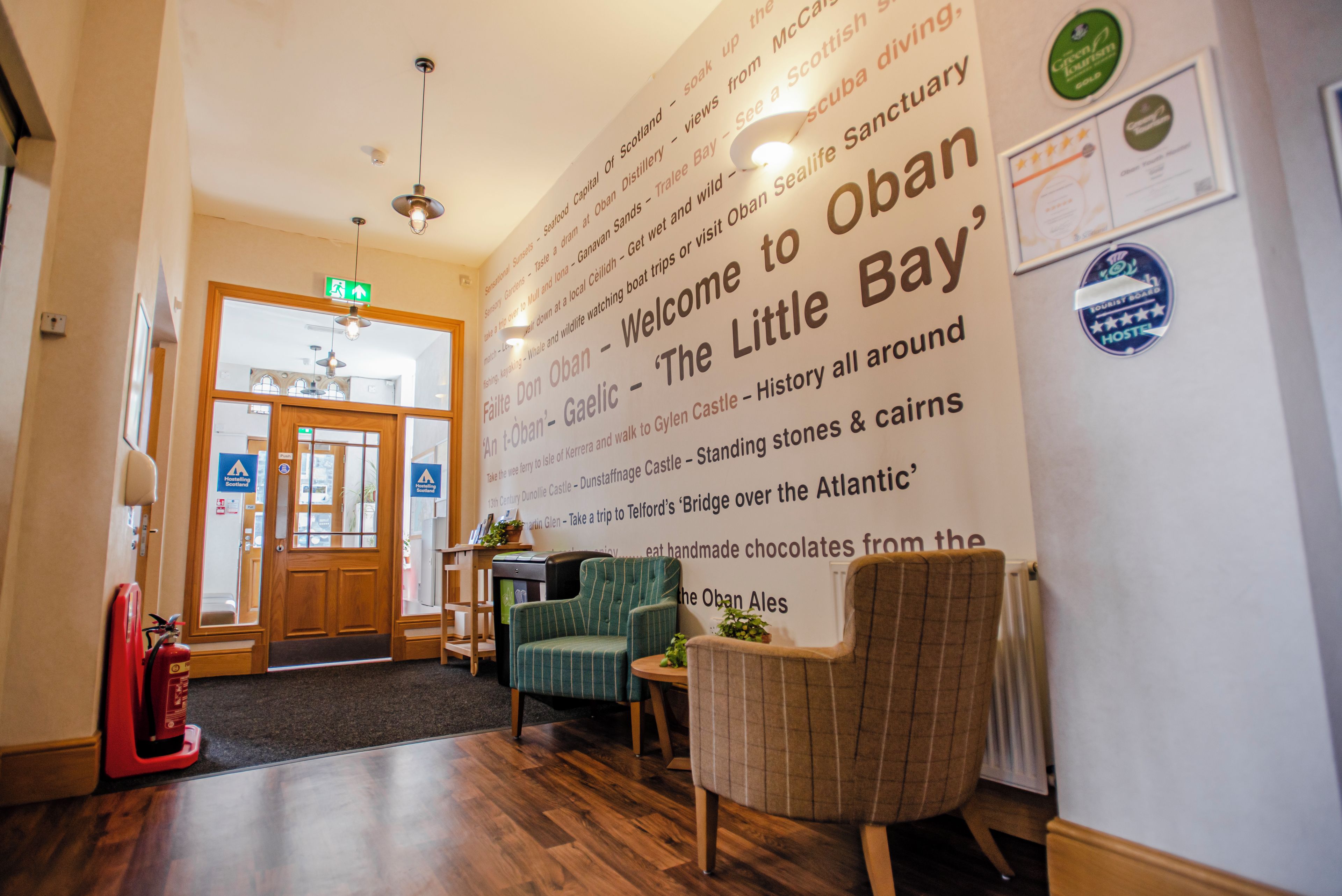 A reception area with a large welcome sign, a fire extinguisher, and a seating area with a table and chairs.