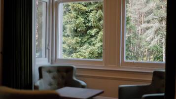 A room with a view of a forest through large windows.