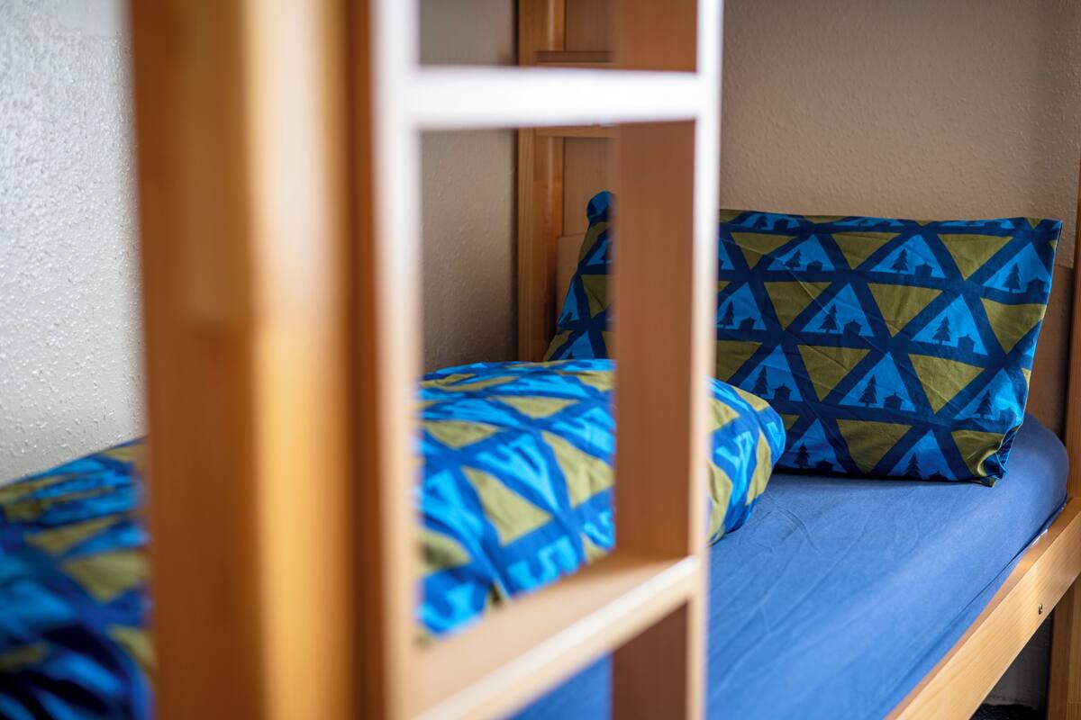 A bunk bed with a blue mattress and patterned pillows.