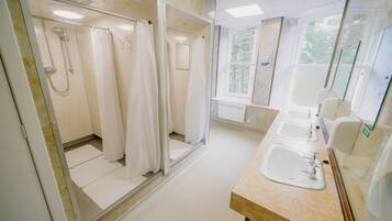 Un baño con ducha, lavamanos y ventana.