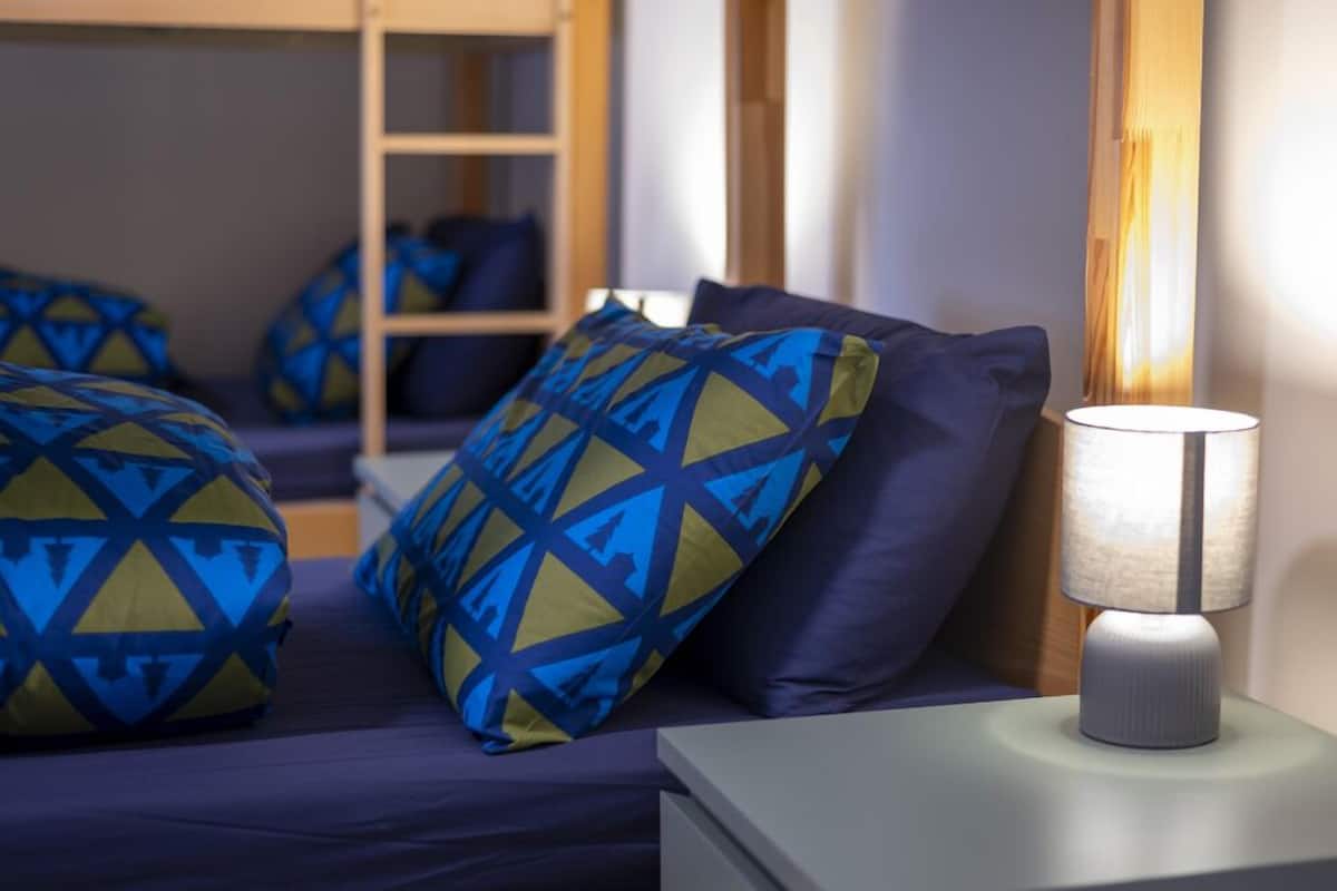 A neatly arranged bedroom with a bed, pillows, and a bedside lamp.