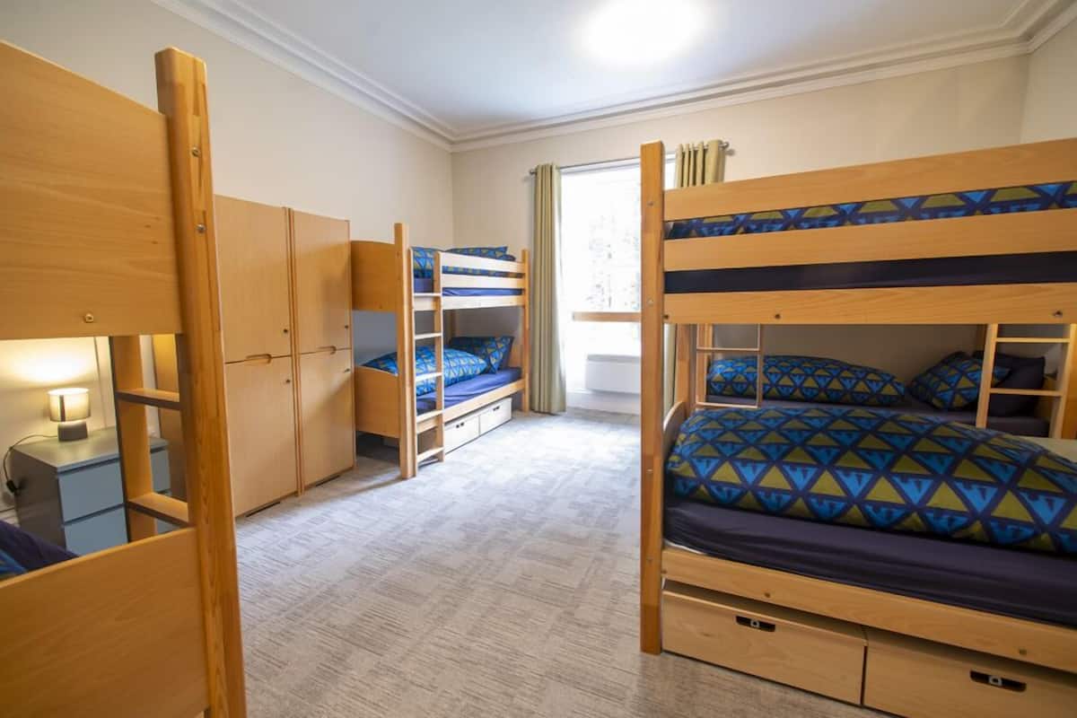 A room with bunk beds, a desk, and a wardrobe.