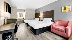 Een hotelkamer met twee bedden, een bureau, een stoel en een televisie.