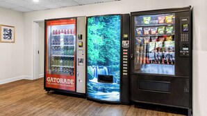 Drie automaten in een ruimte met houten vloer en een wit plafond.